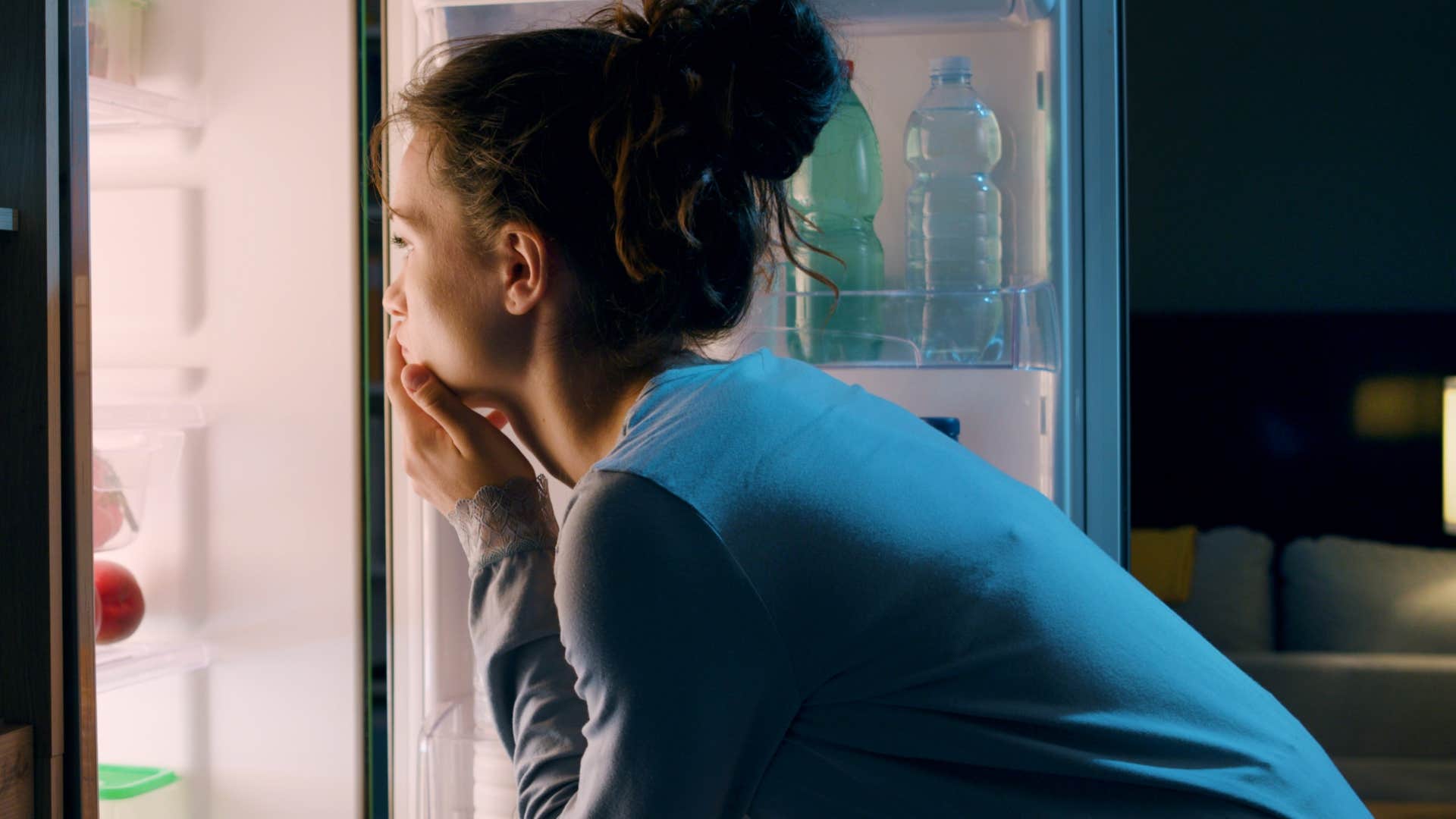 upper middle class woman looking in a garage fridge