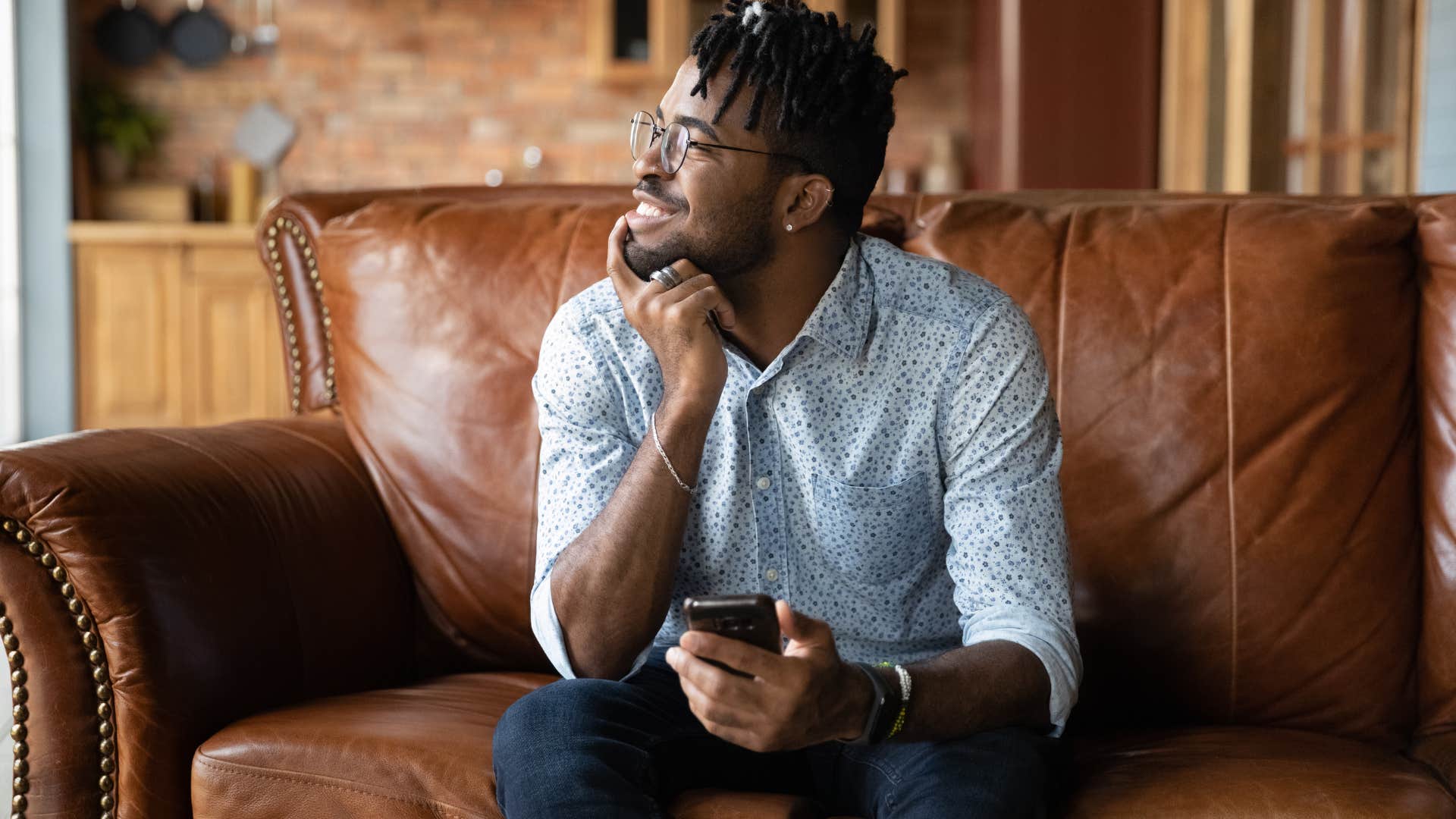 upper middle class man sitting on a leather couch at home