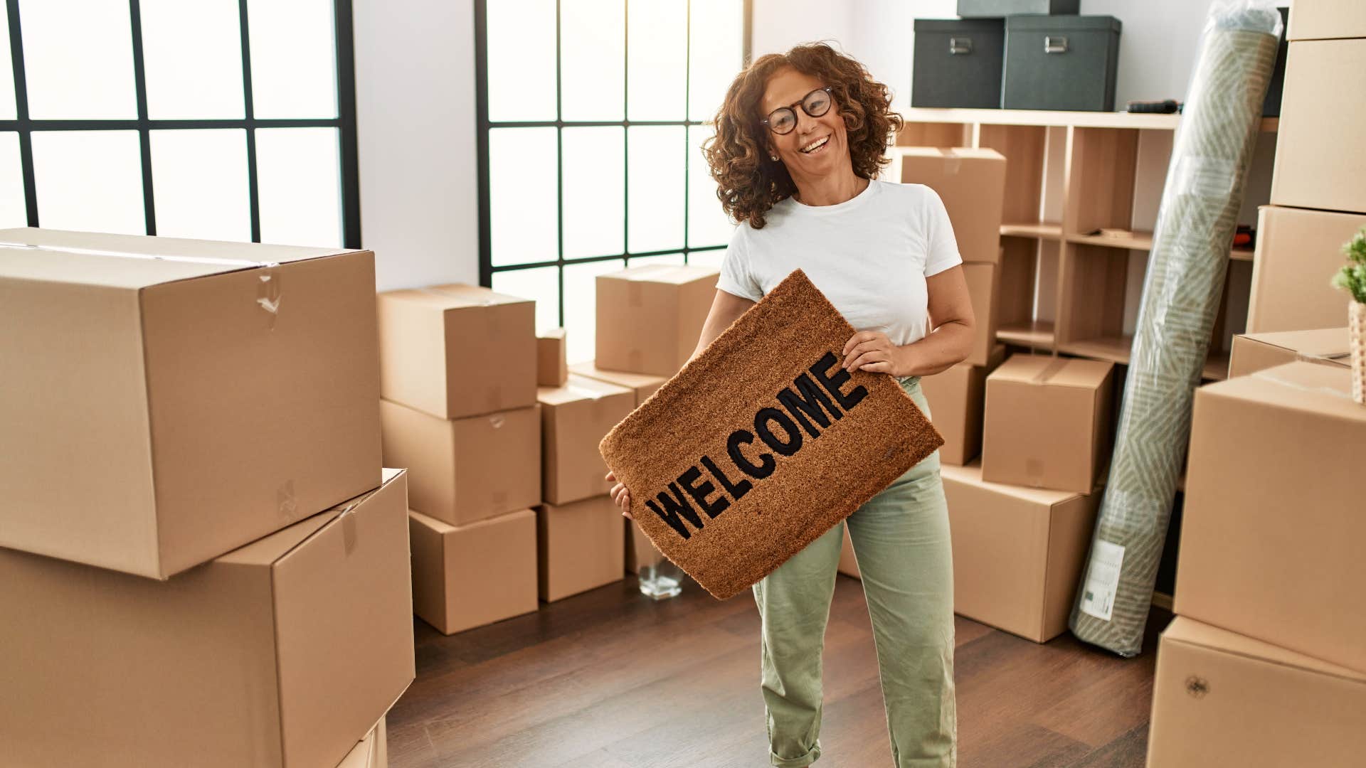 woman holding up welcome mat after moving