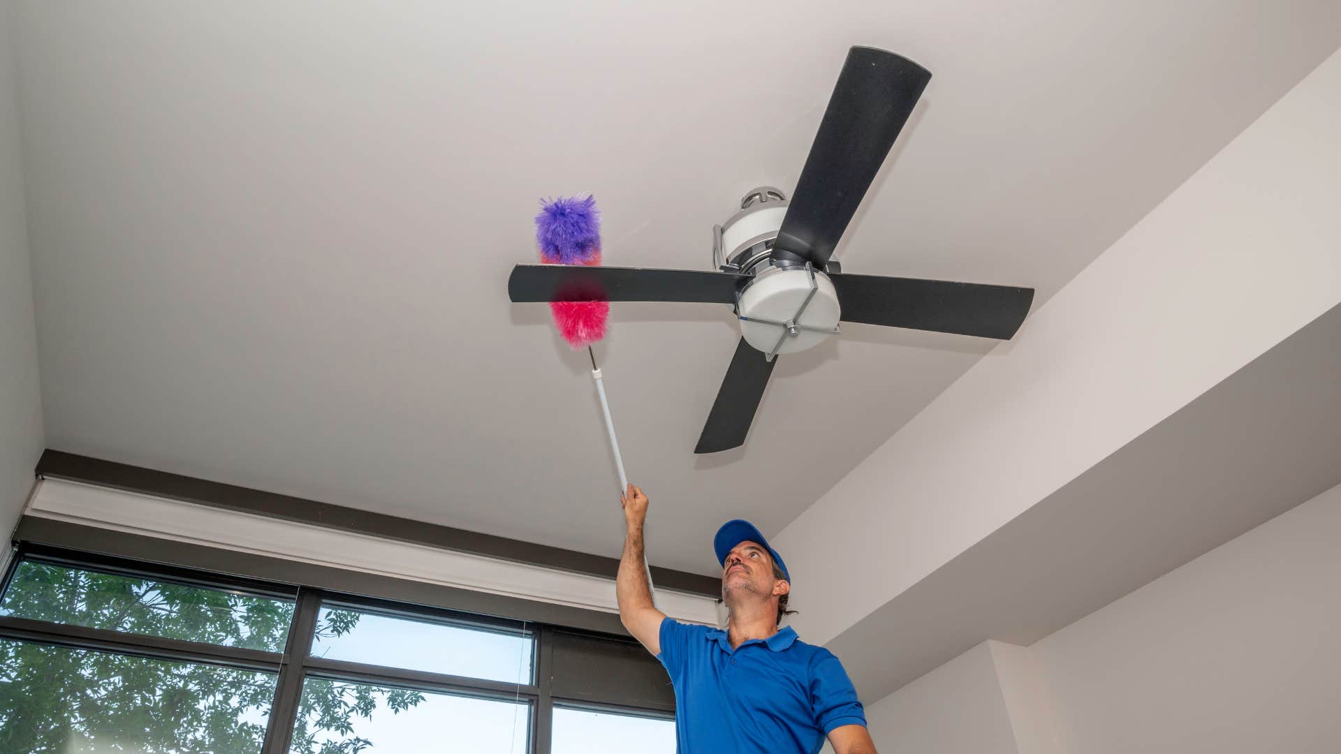 man dusting ceiling fan