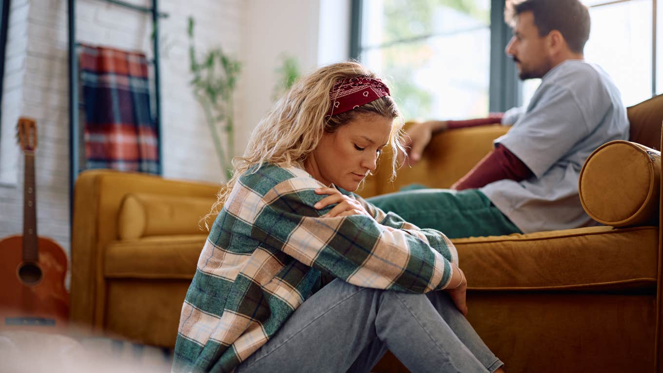 upset woman sitting on floor away isolated by partner