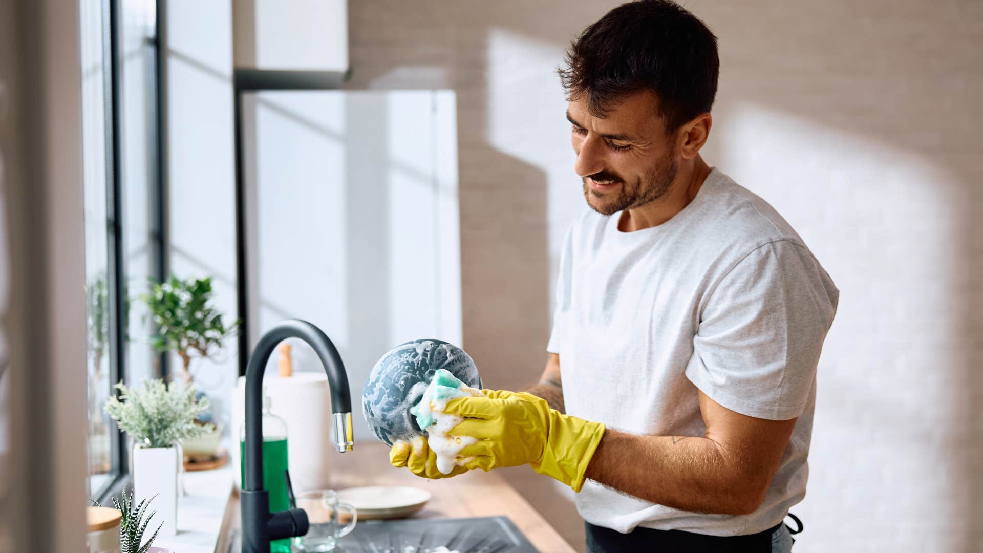 man washing dishes picking up household slack