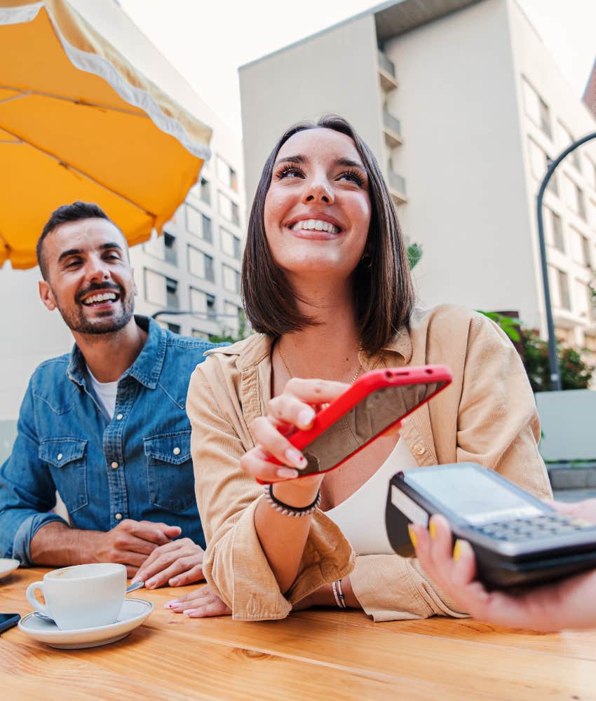 Happy couple pay at restaurant showing opposite money issues