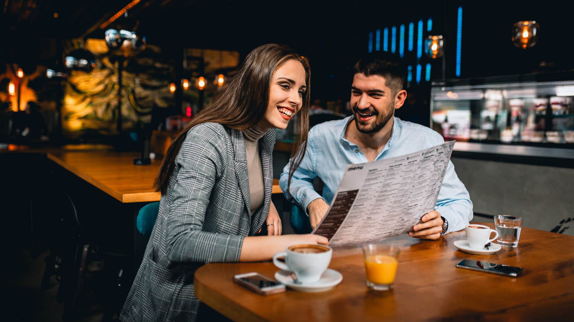 woman looking at the man and refusing to order more courses than the host unless he invites her to