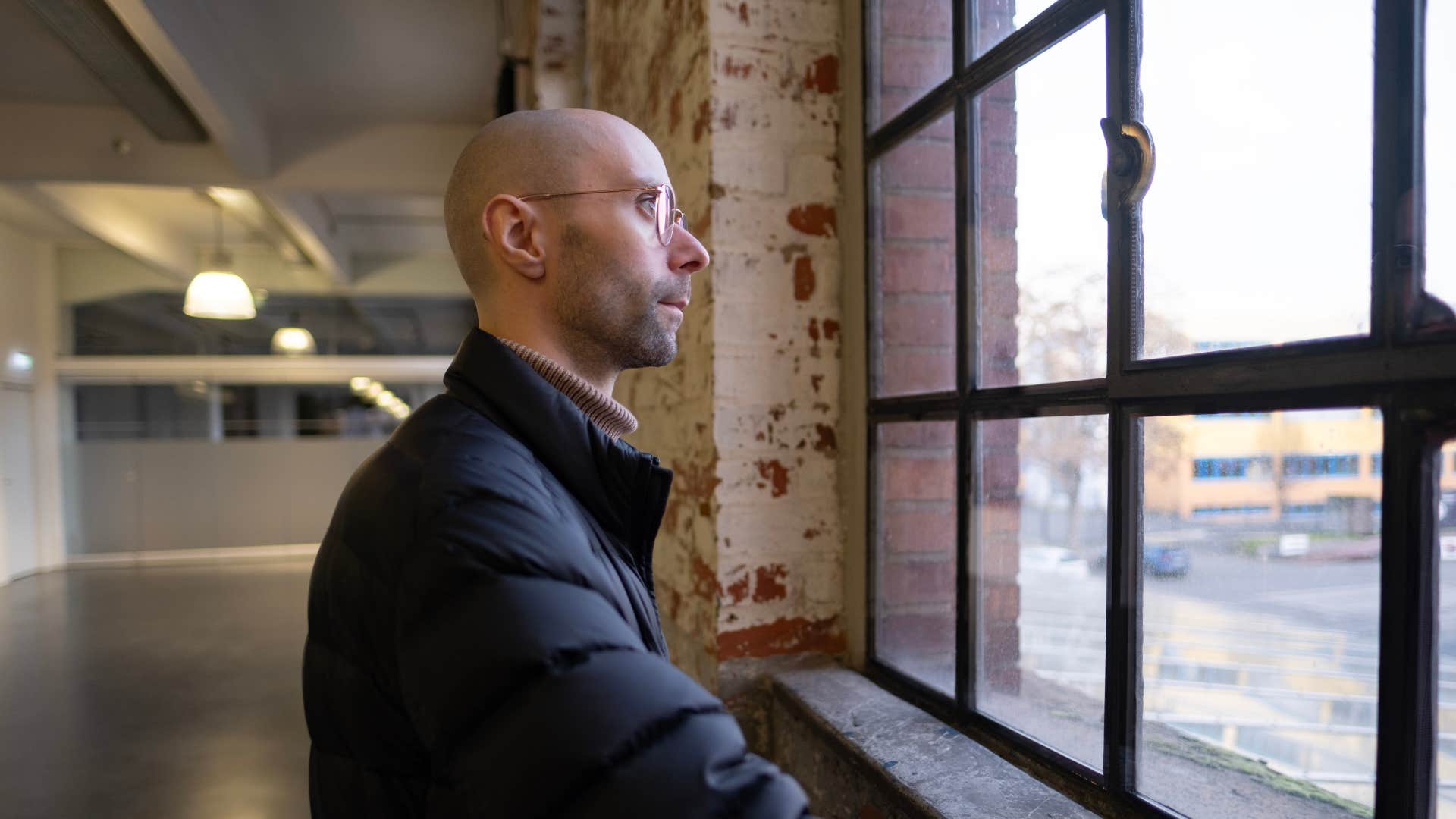 man hyper aware of his surroundings looking out window