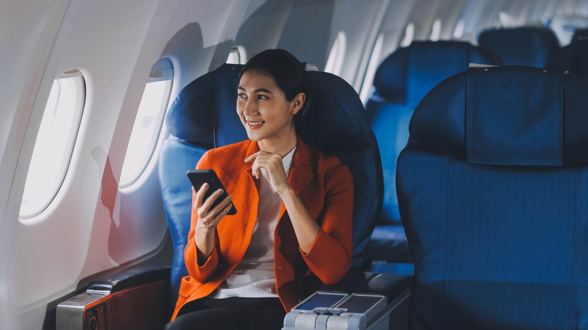 happy woman sitting on plane in first class