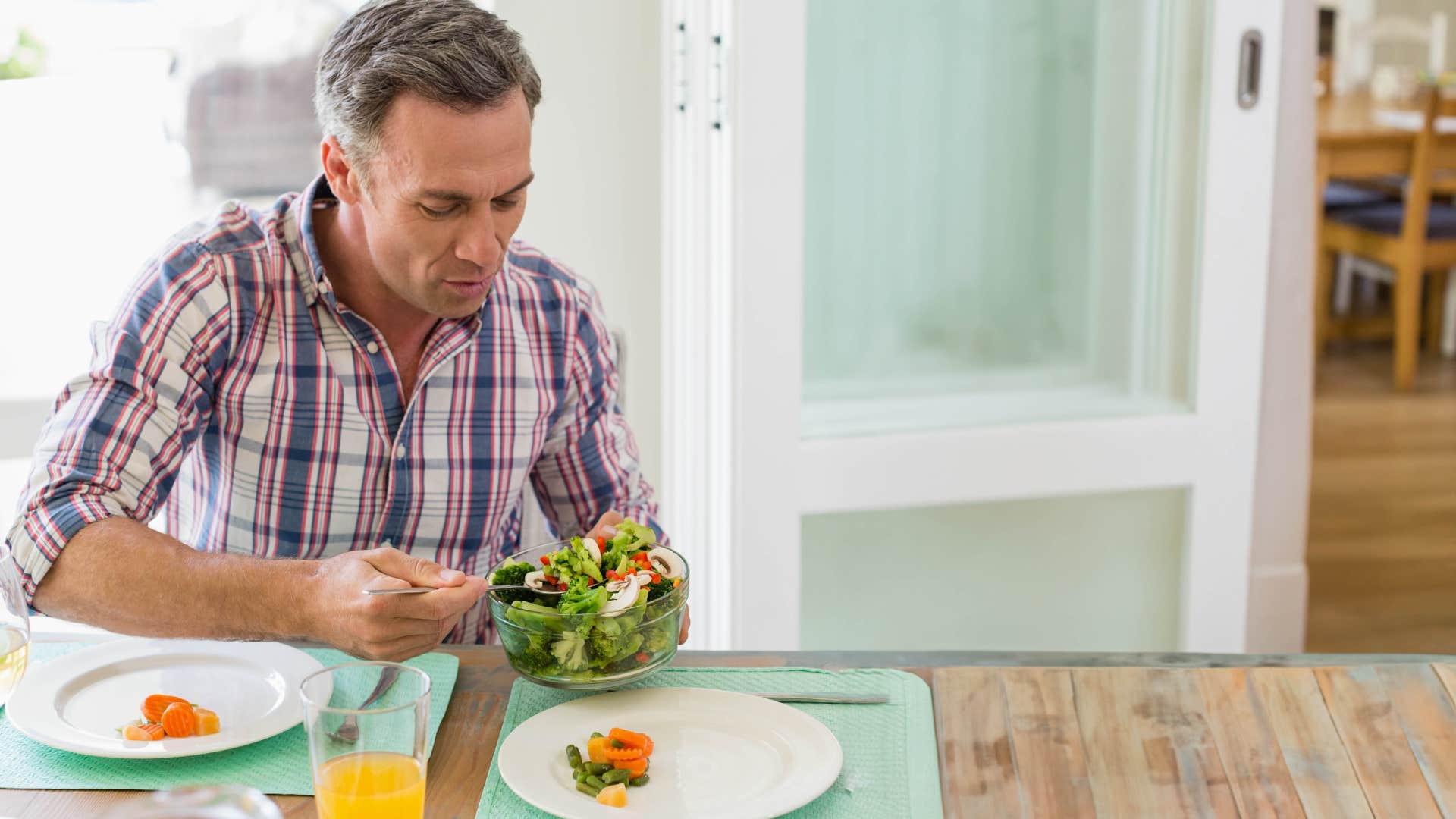 man eating a salad out of glass container