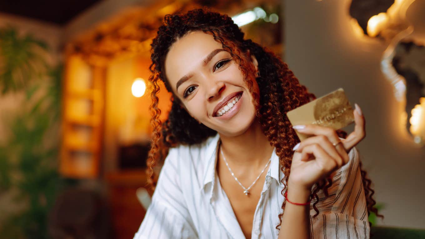 happy frugal woman holding credit card smiling