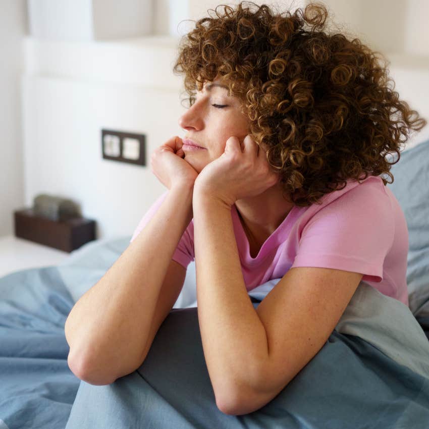 Woman listening to their body while resting in bed.