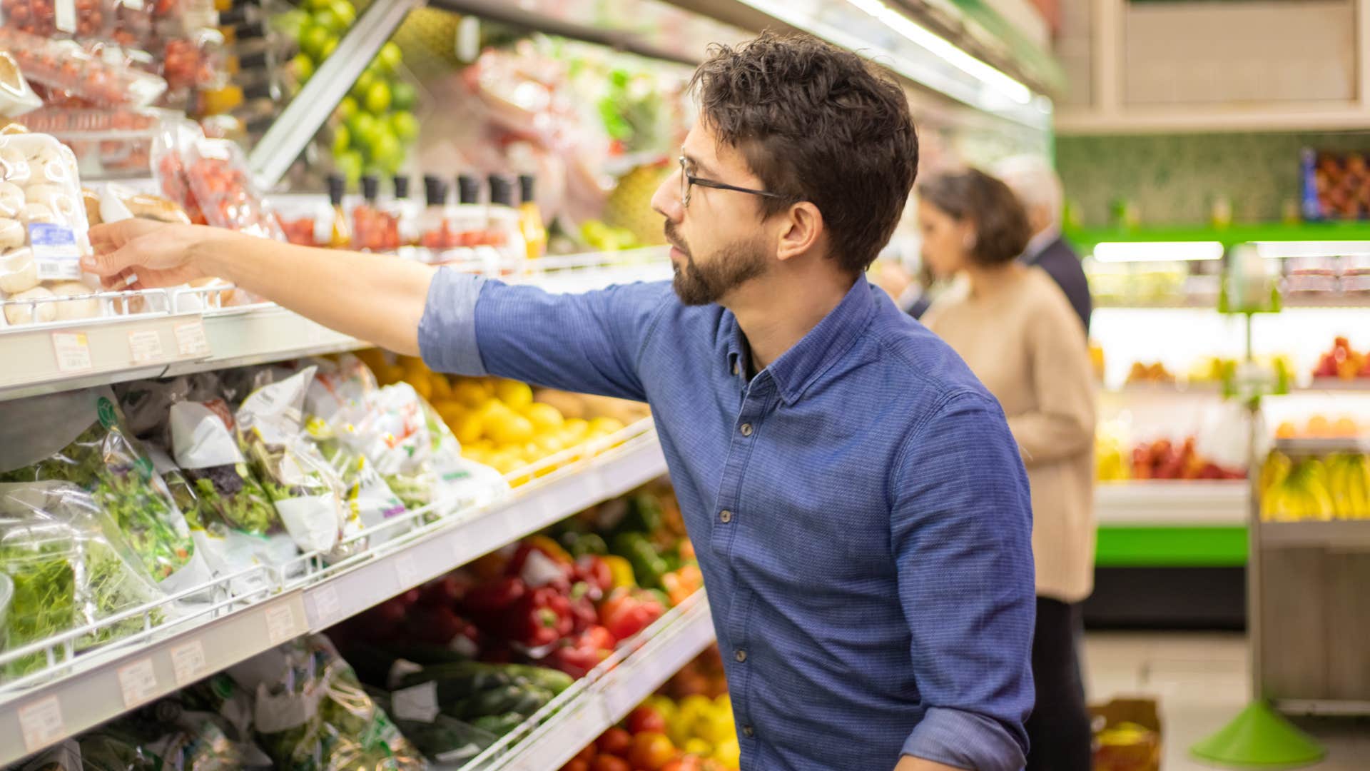 man picking up organic foods at grocery store
