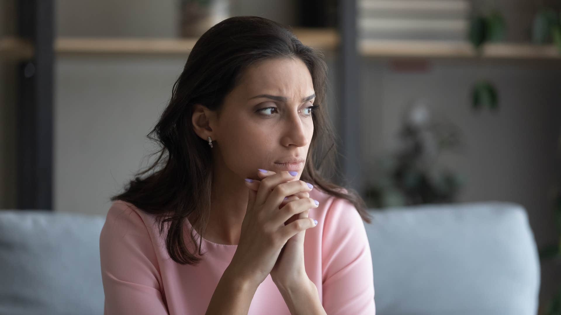 woman in pink worrying about passing on generational trauma as she thinks deeply