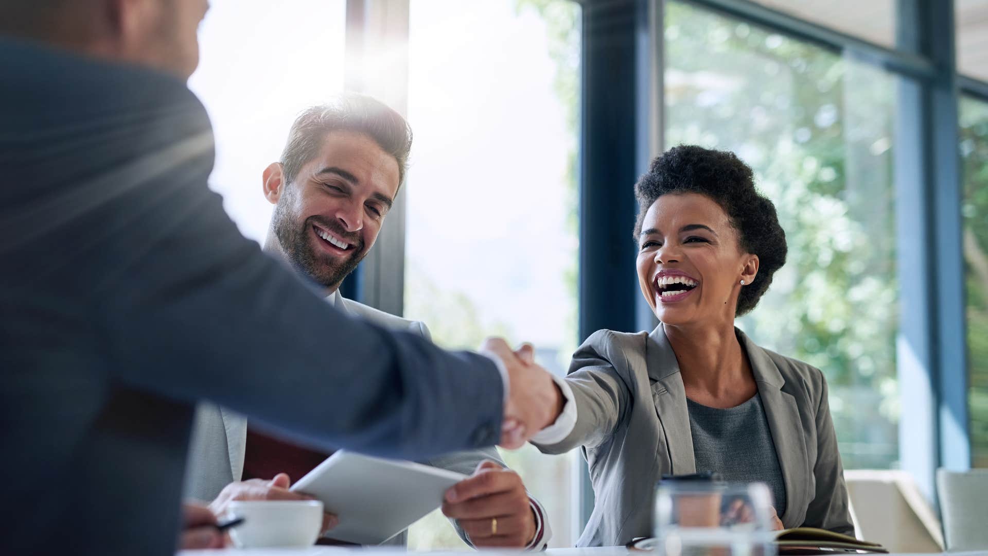 woman shakes hand with man as she expects good treatment by default