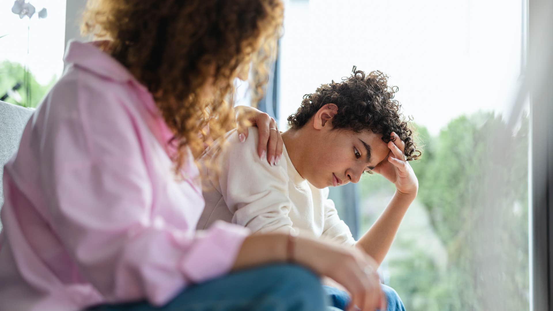 mom in pink confusing gentle with permissive parenting as she comforts upset teenager