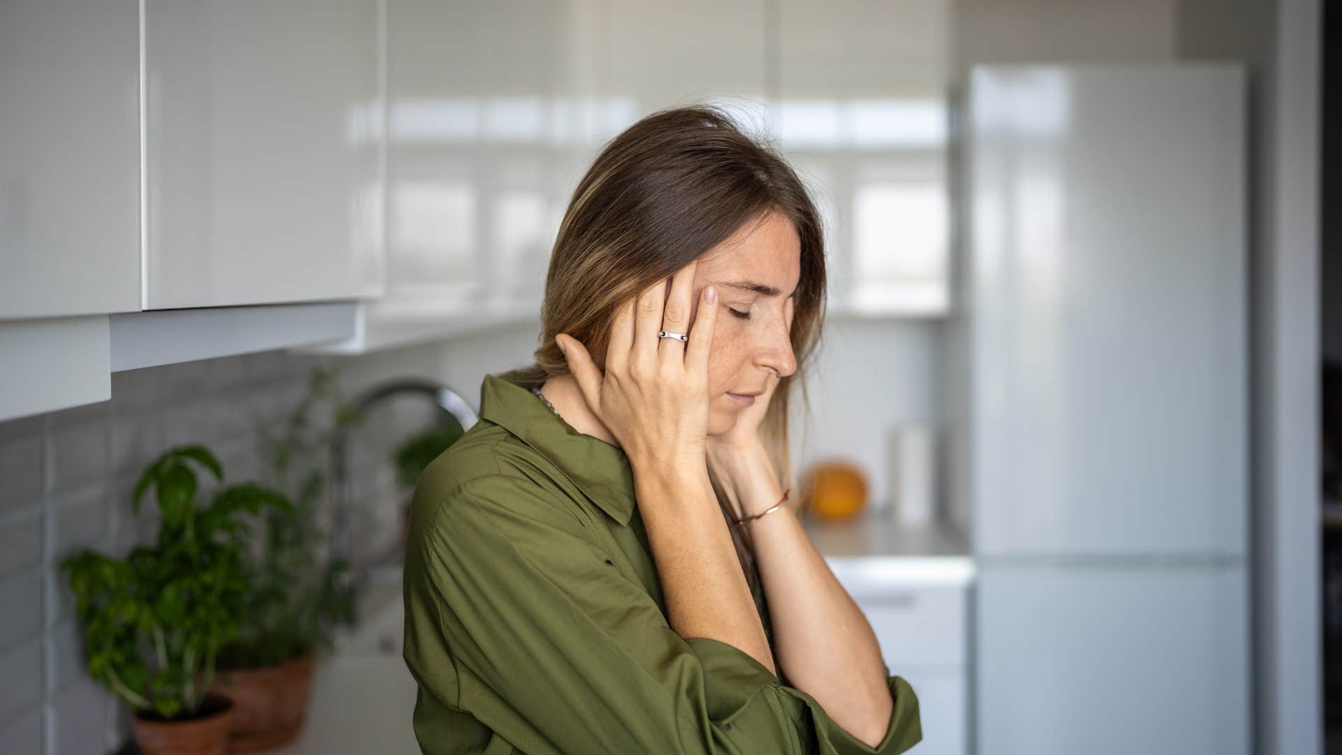 overwhelmed woman sitting in her kitchen