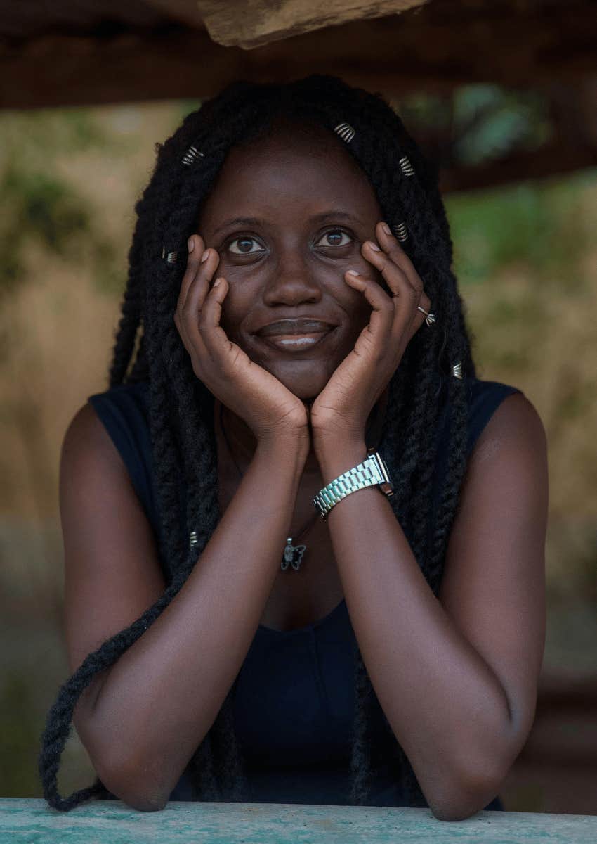 woman with dreads holding her face in her hands