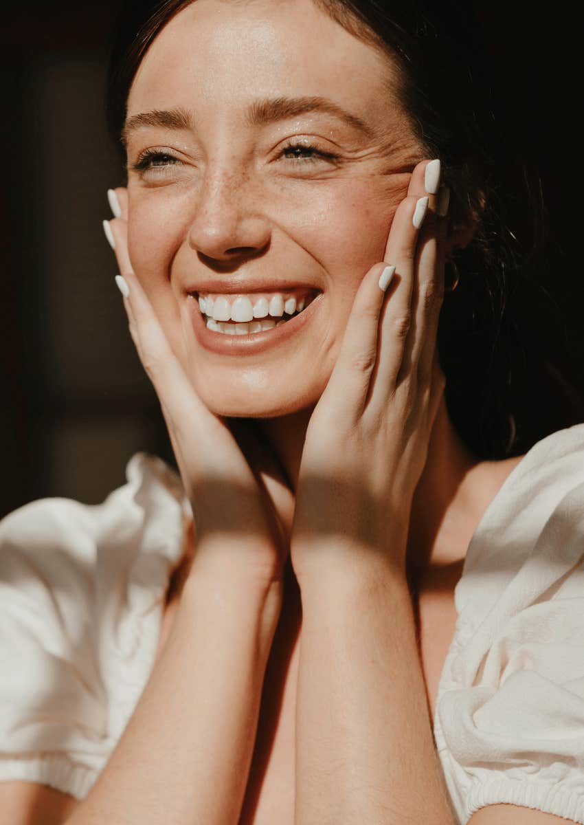 woman with a huge smile and her hands on her face