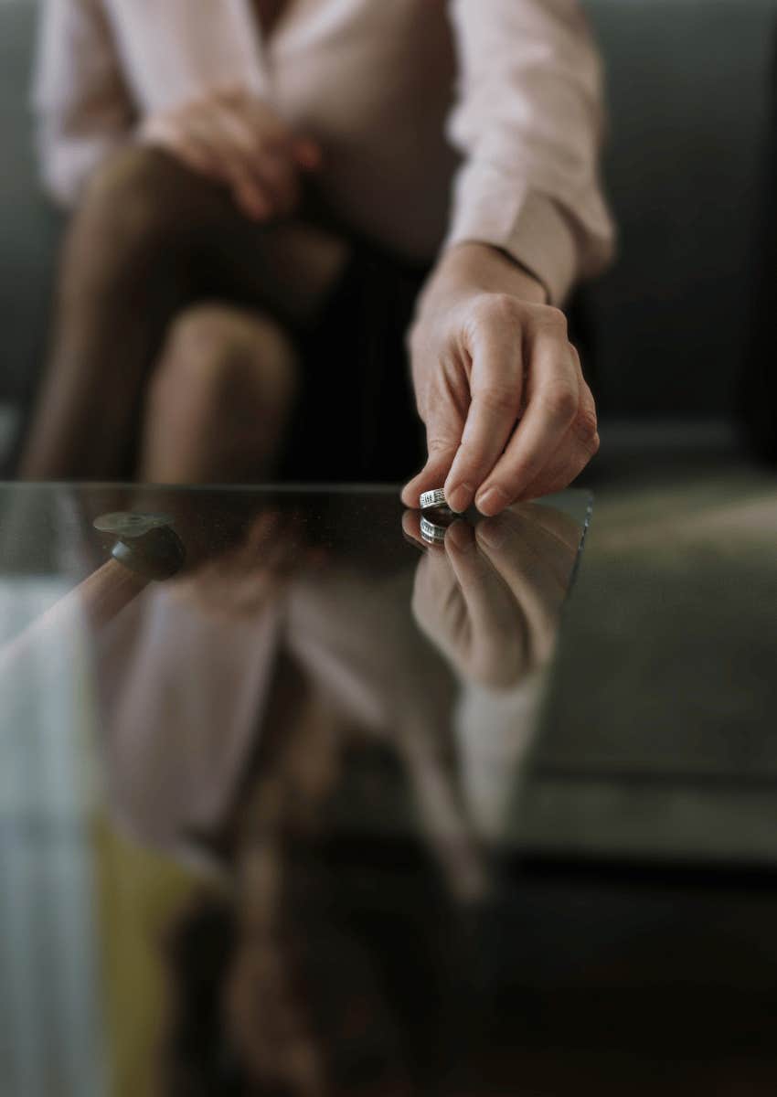 woman setting wedding band down on glass table