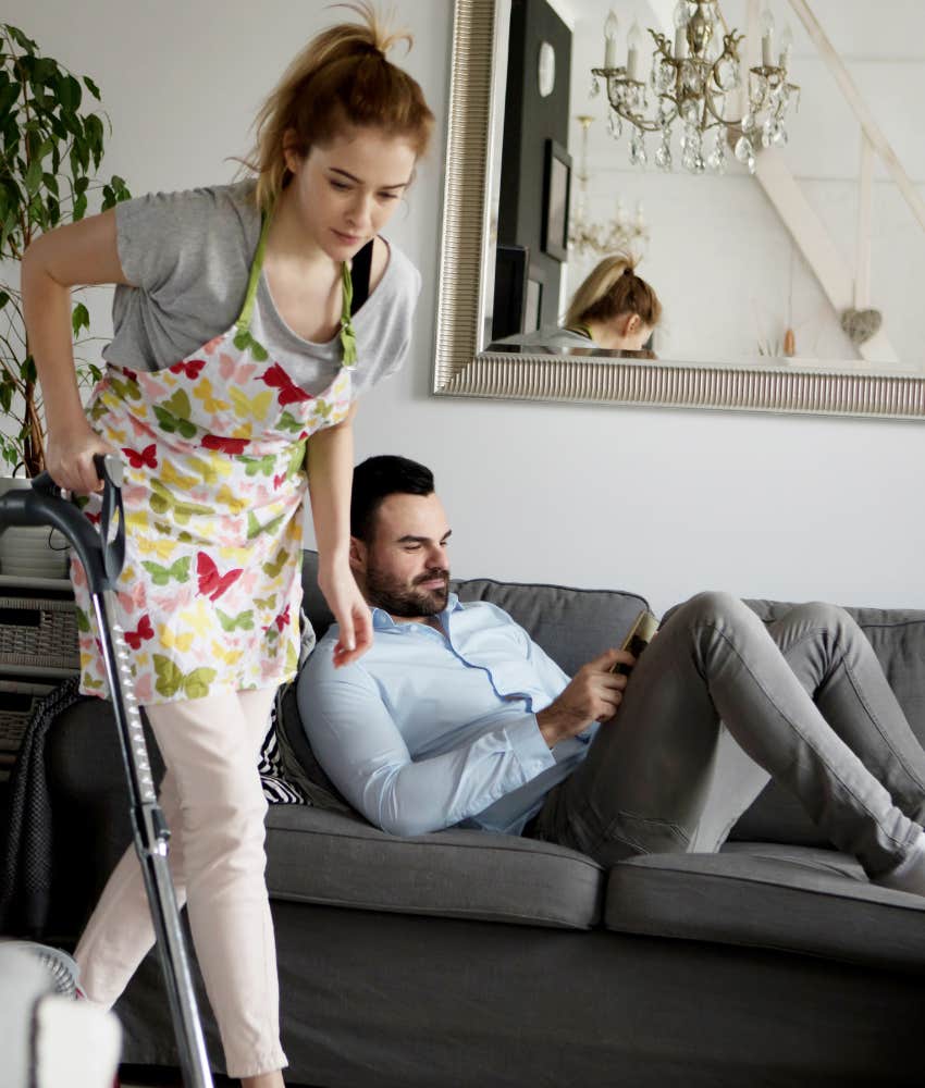 Woman stress cleaning while her husband relaxes on the couch