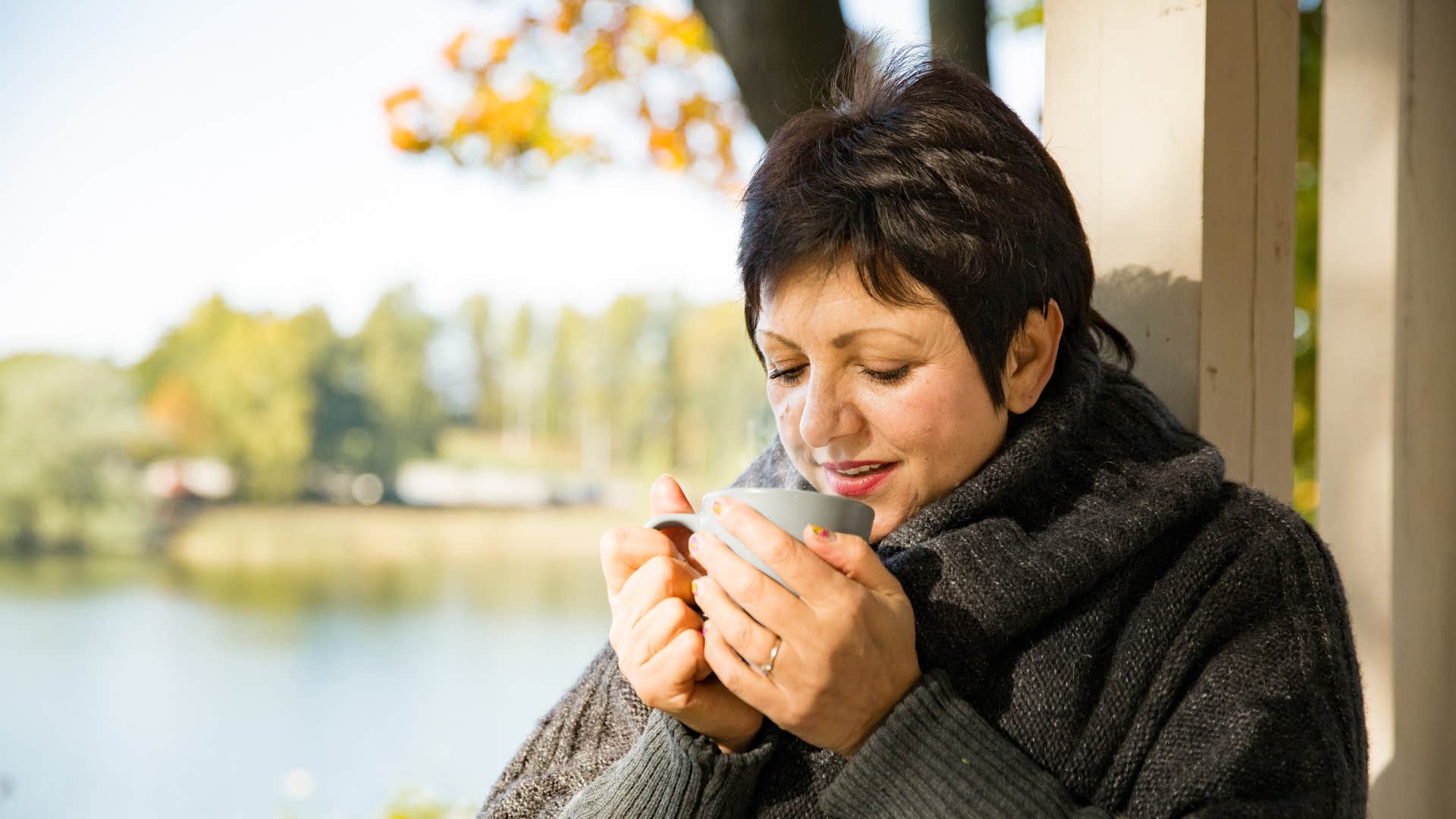 woman in comfort clothes standing outside with tea