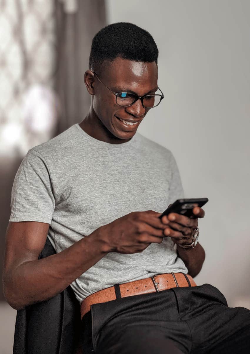 young man smiling down at his phone