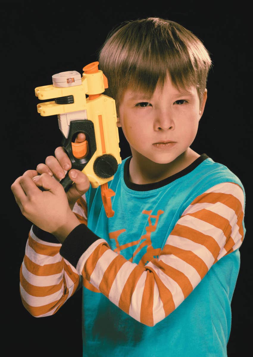 young 90s boy holding a toy gun