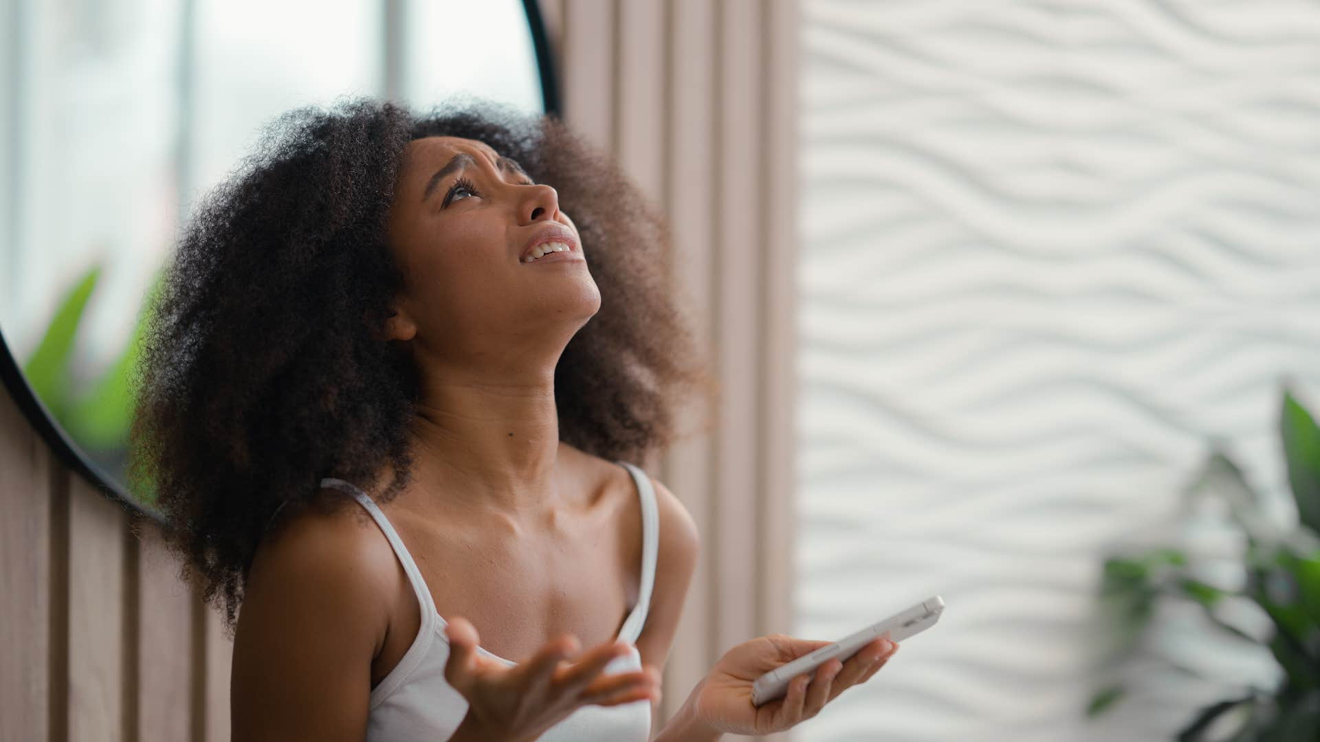 frustrated woman looking at ceiling holding phone