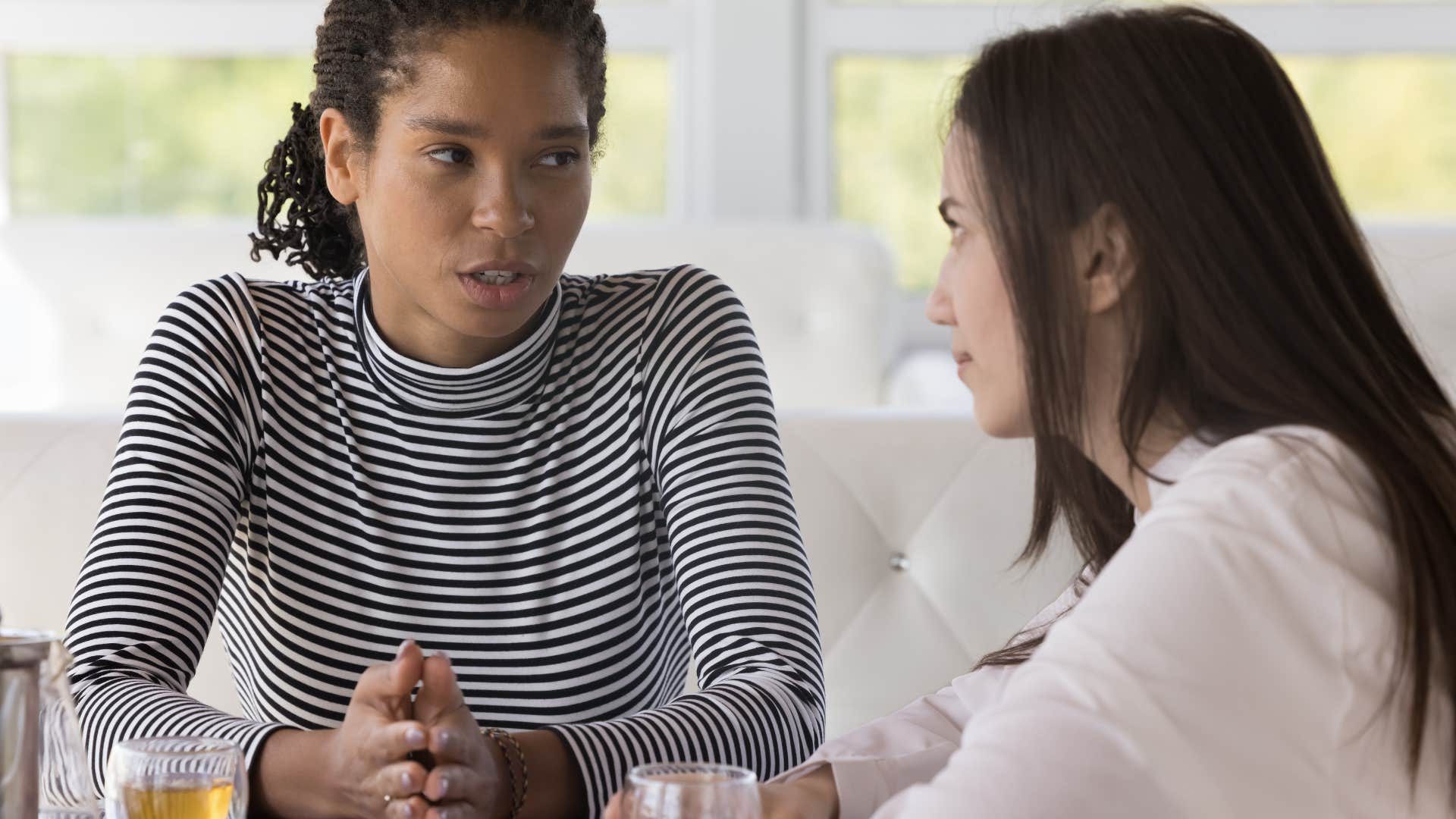woman having serious conversation with friend sitting at table