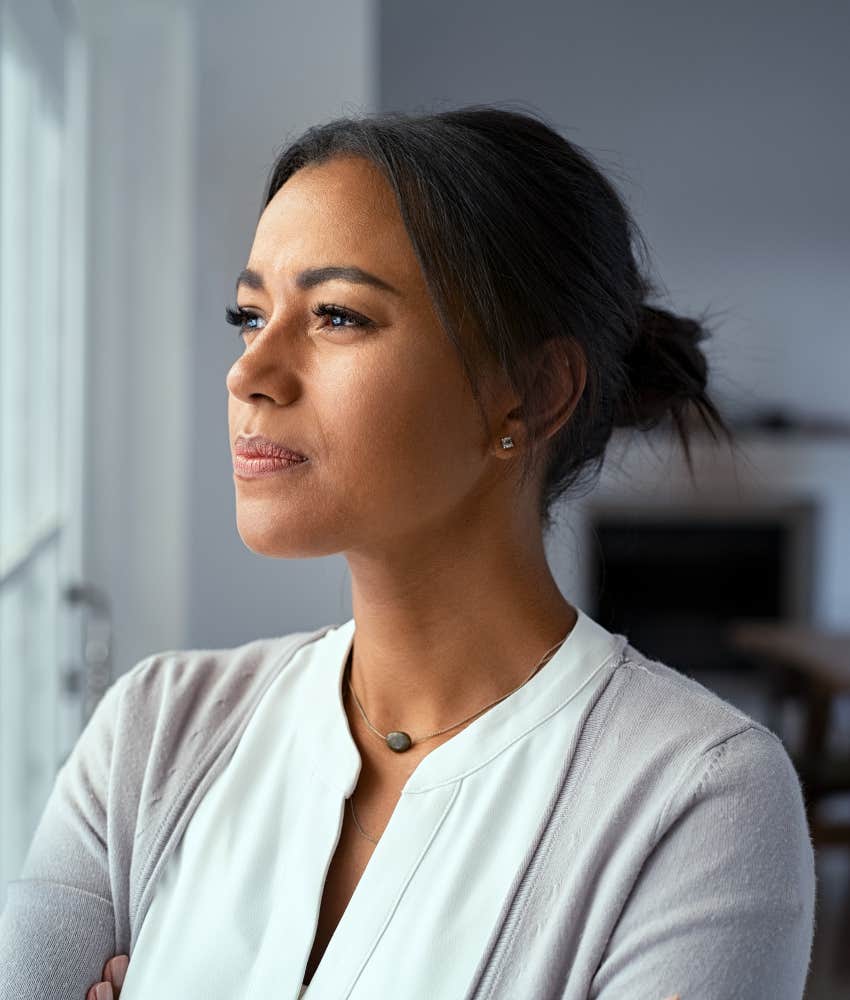 intelligent woman with anxiety looking out of window while thinking