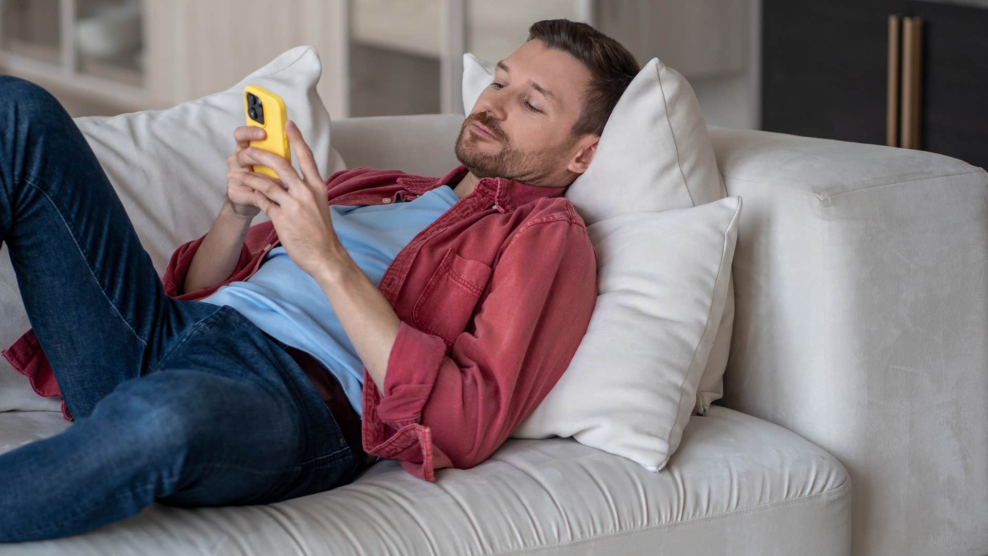 man laying on couch canceling plans via text