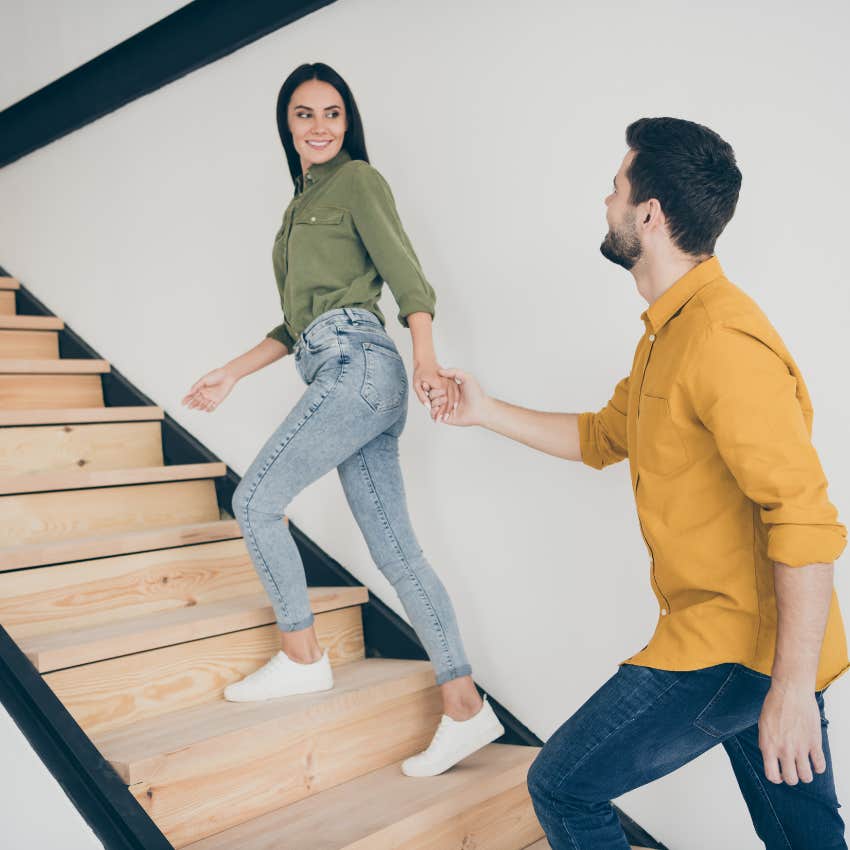 man offering woman help up the stairs