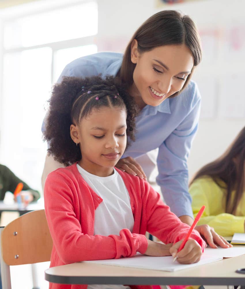 teacher helping student learn cursive writing at school
