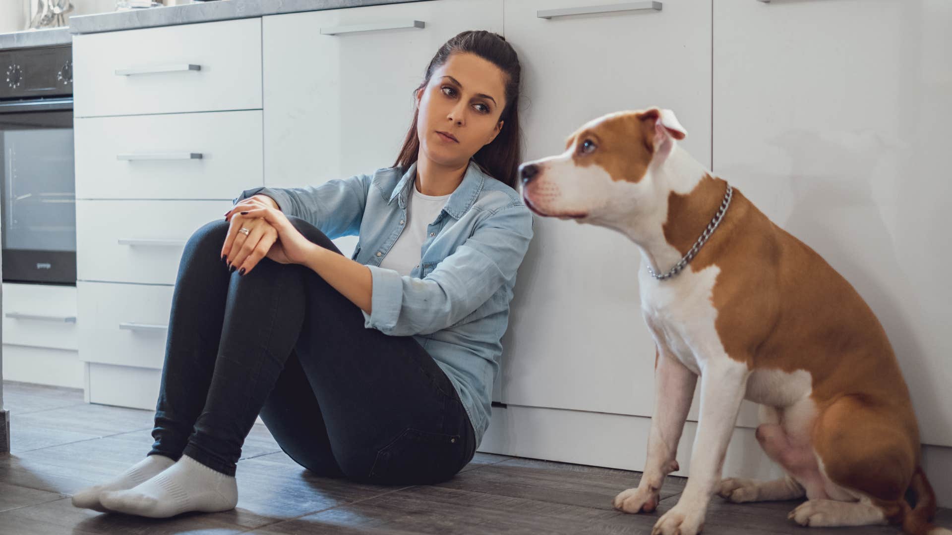 woman sitting next to dog in kitchen respecting his boundaries