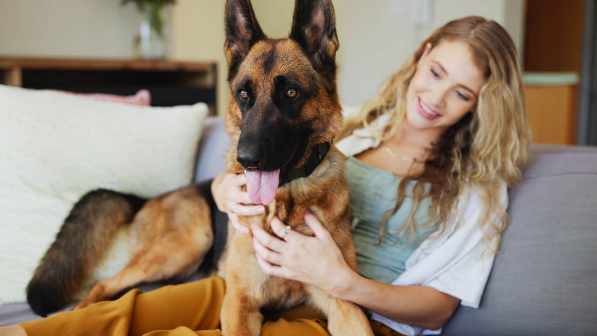 woman sitting on couch holding her german shepherd