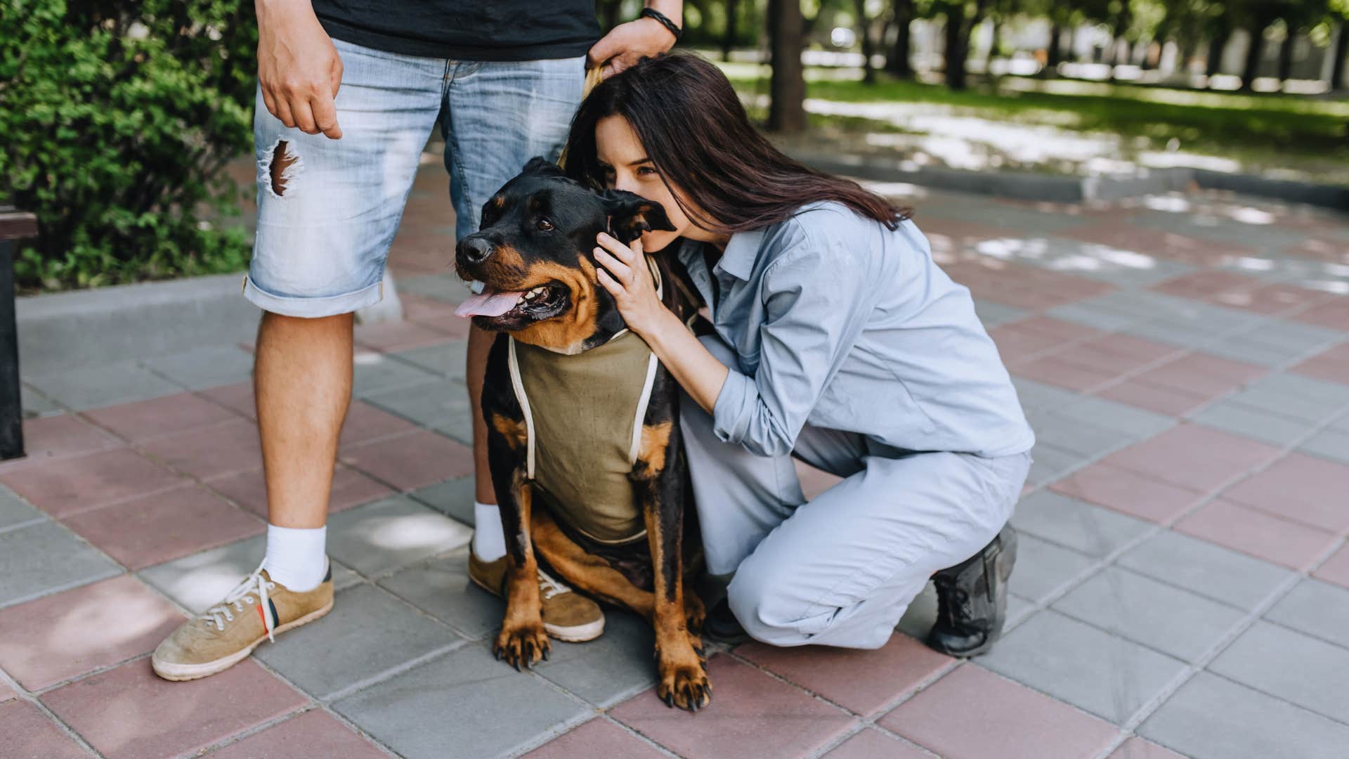 woman kissing rottweiler dog's head outside