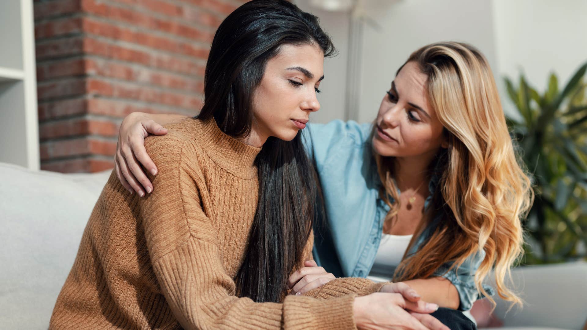 woman comforting overly emotional friend on couch