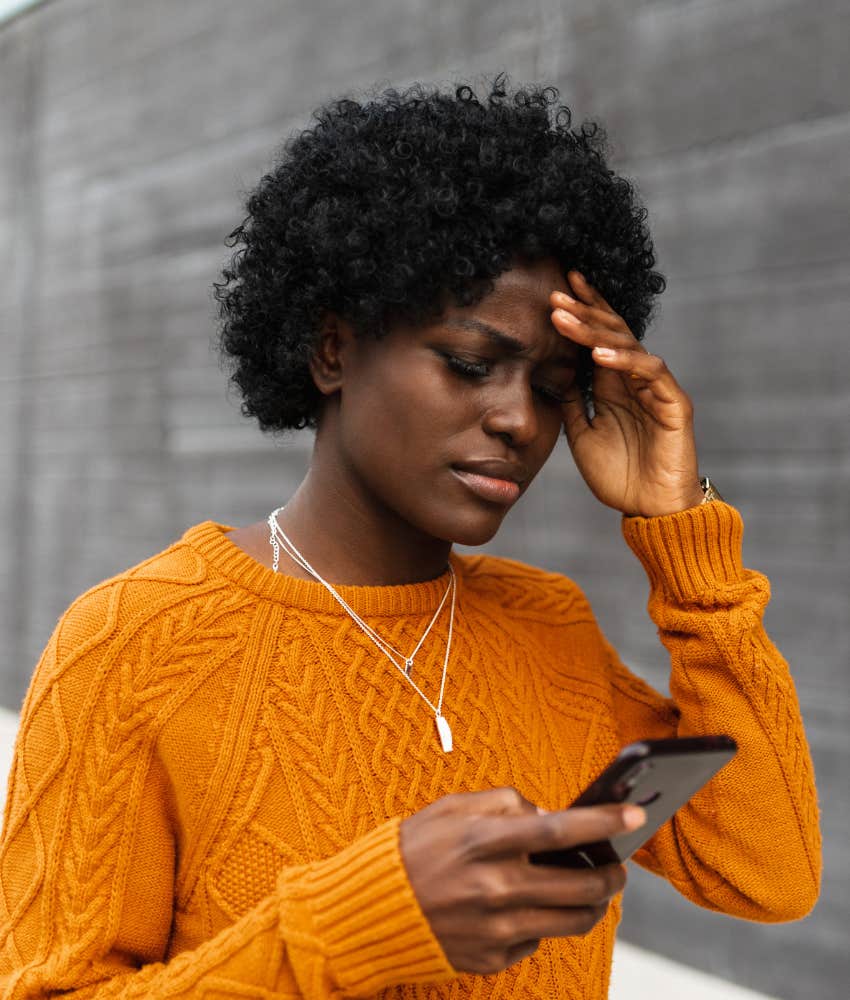 Upset person checks mobile phone showing grief at losing friend