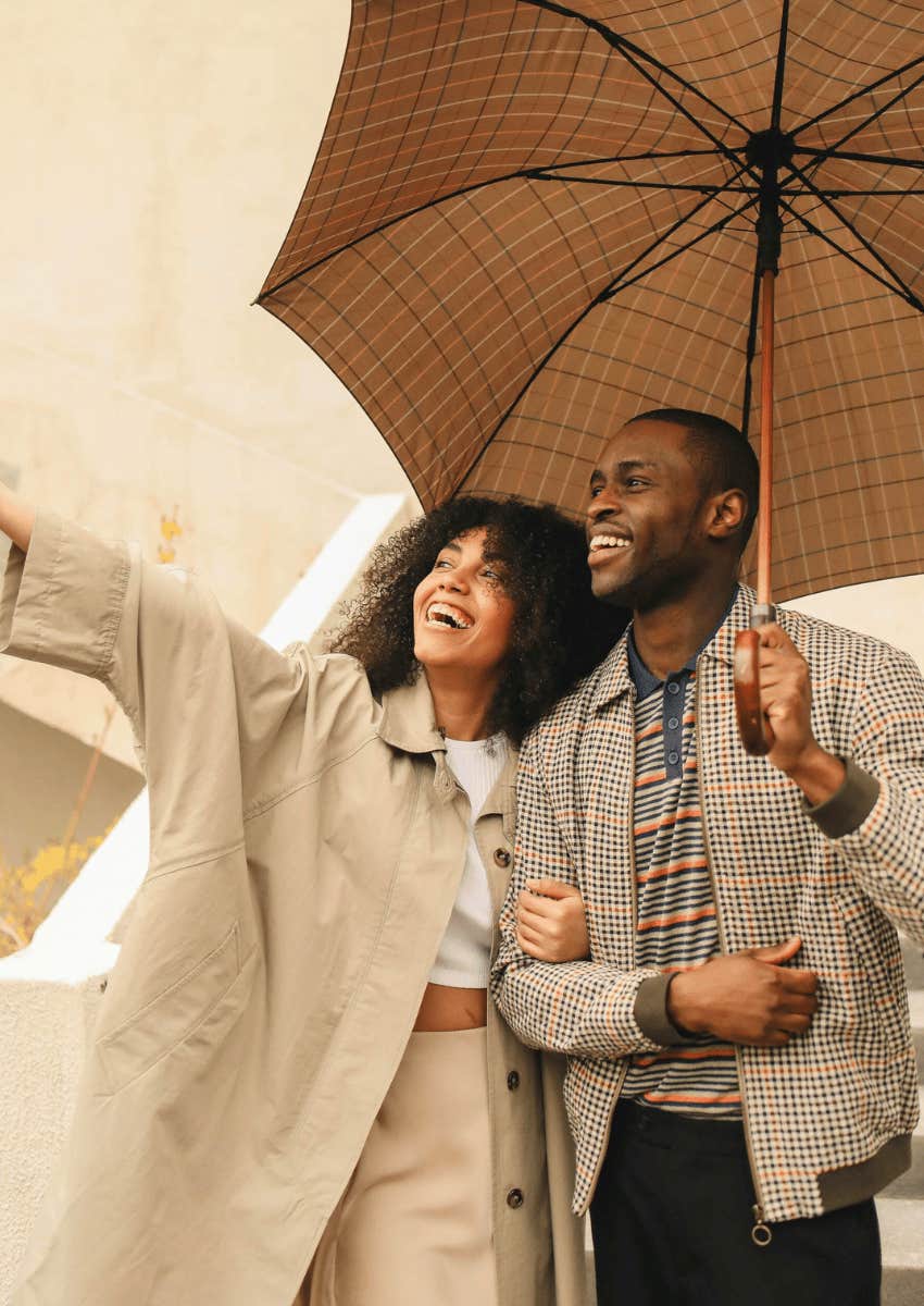 happy couple standing together under umbrella