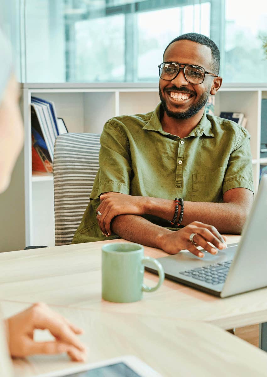 happy man smiling at another person in office
