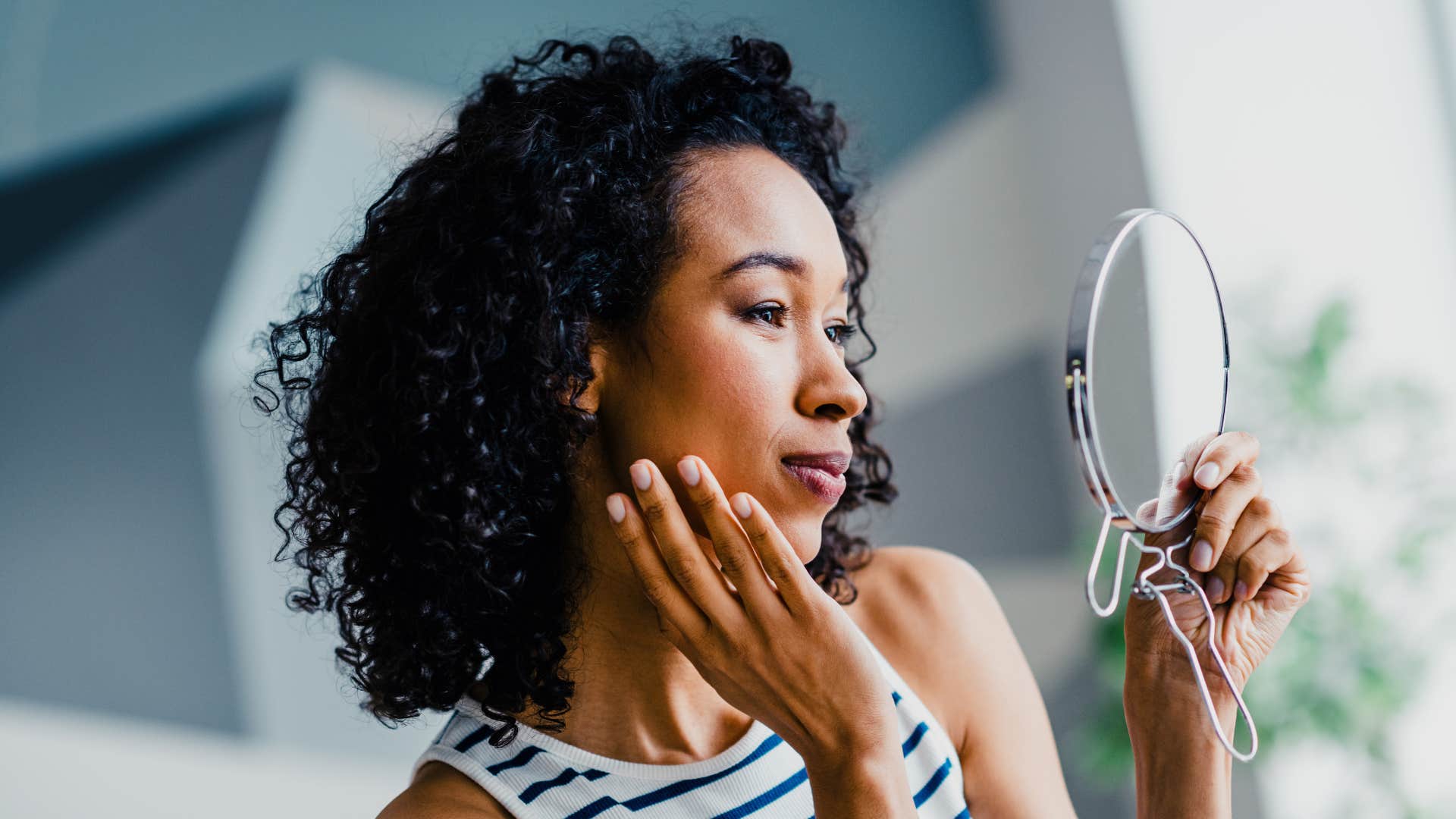 woman in stripped shirt self conscious of appearance due to partner as she checks herself in the mirror