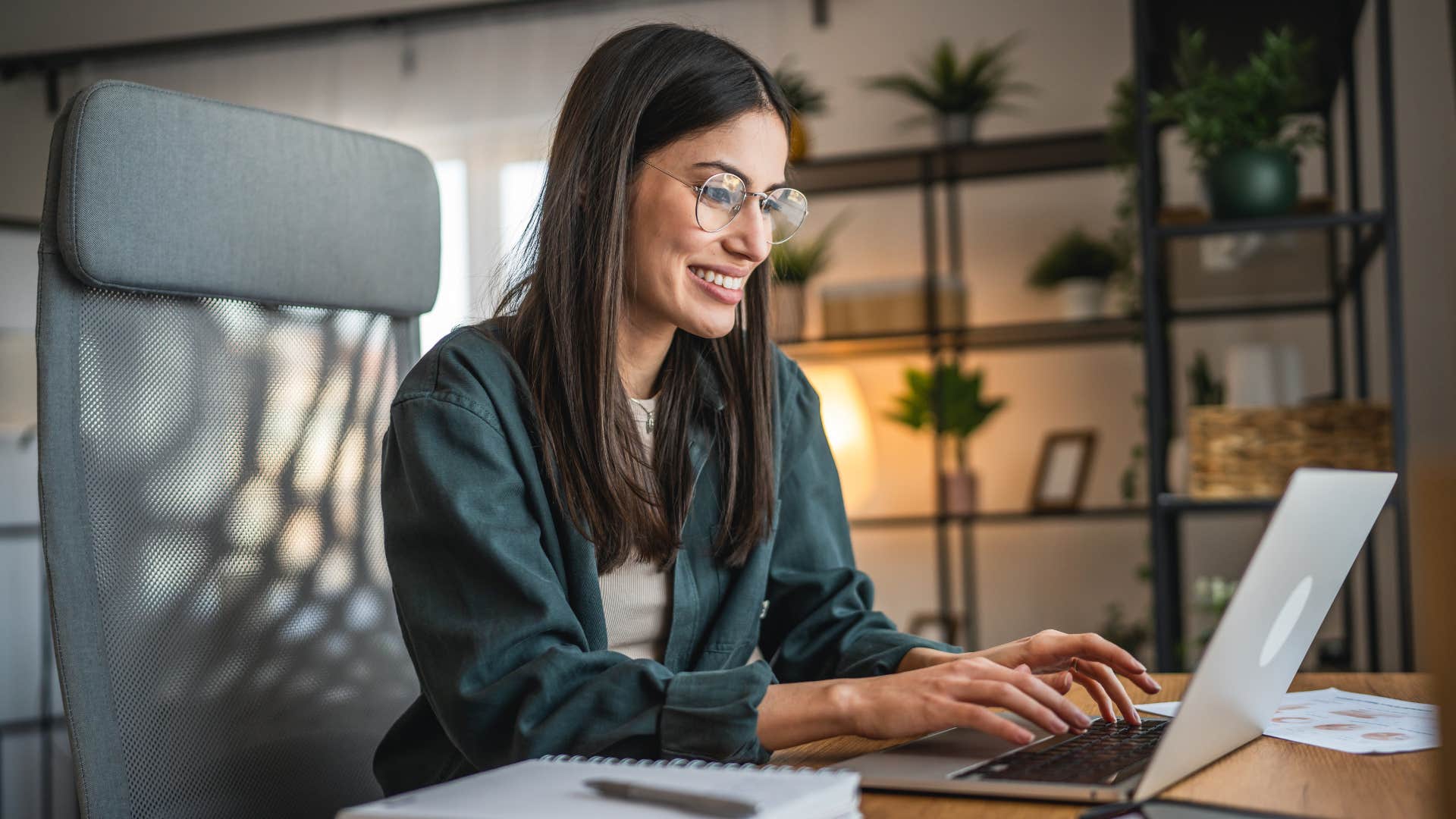 woman in green working towards her dreams and ambitions as she types on laptop