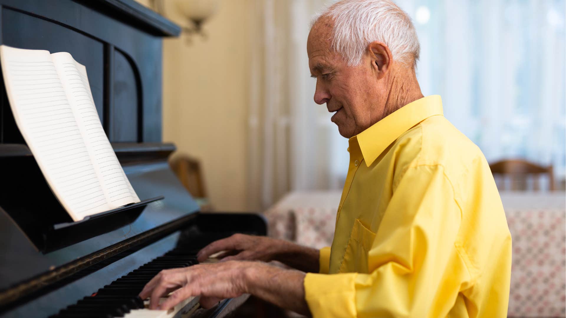 older man playing piano at home