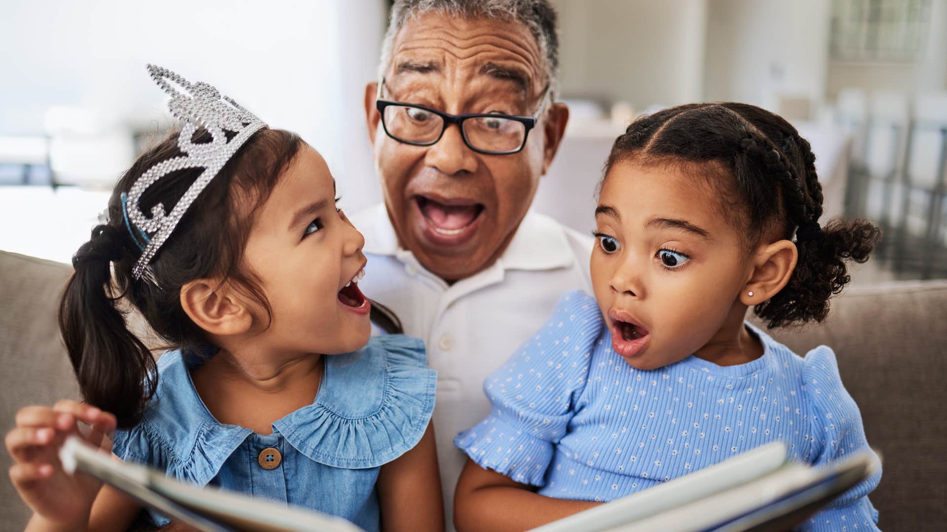 grandpa reading books with his excited granddaughters