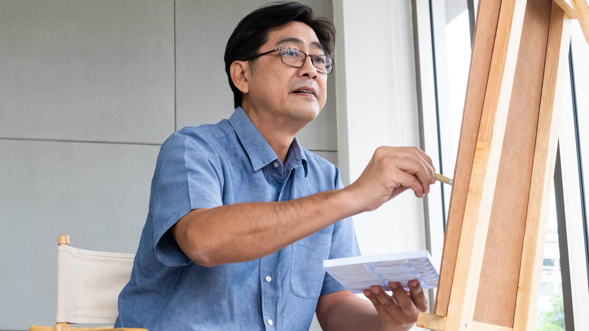 man drawing and painting on a canvas at home