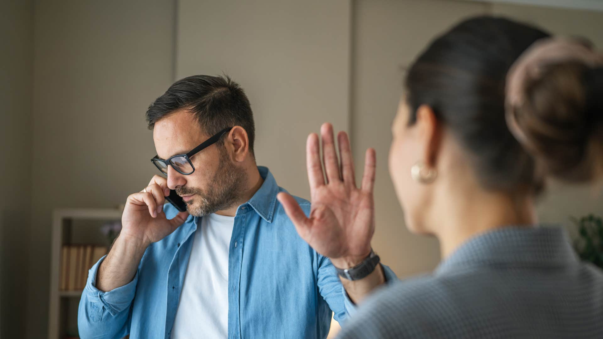Person on phone puts up hand putting others first showing relationship hanging by a thread