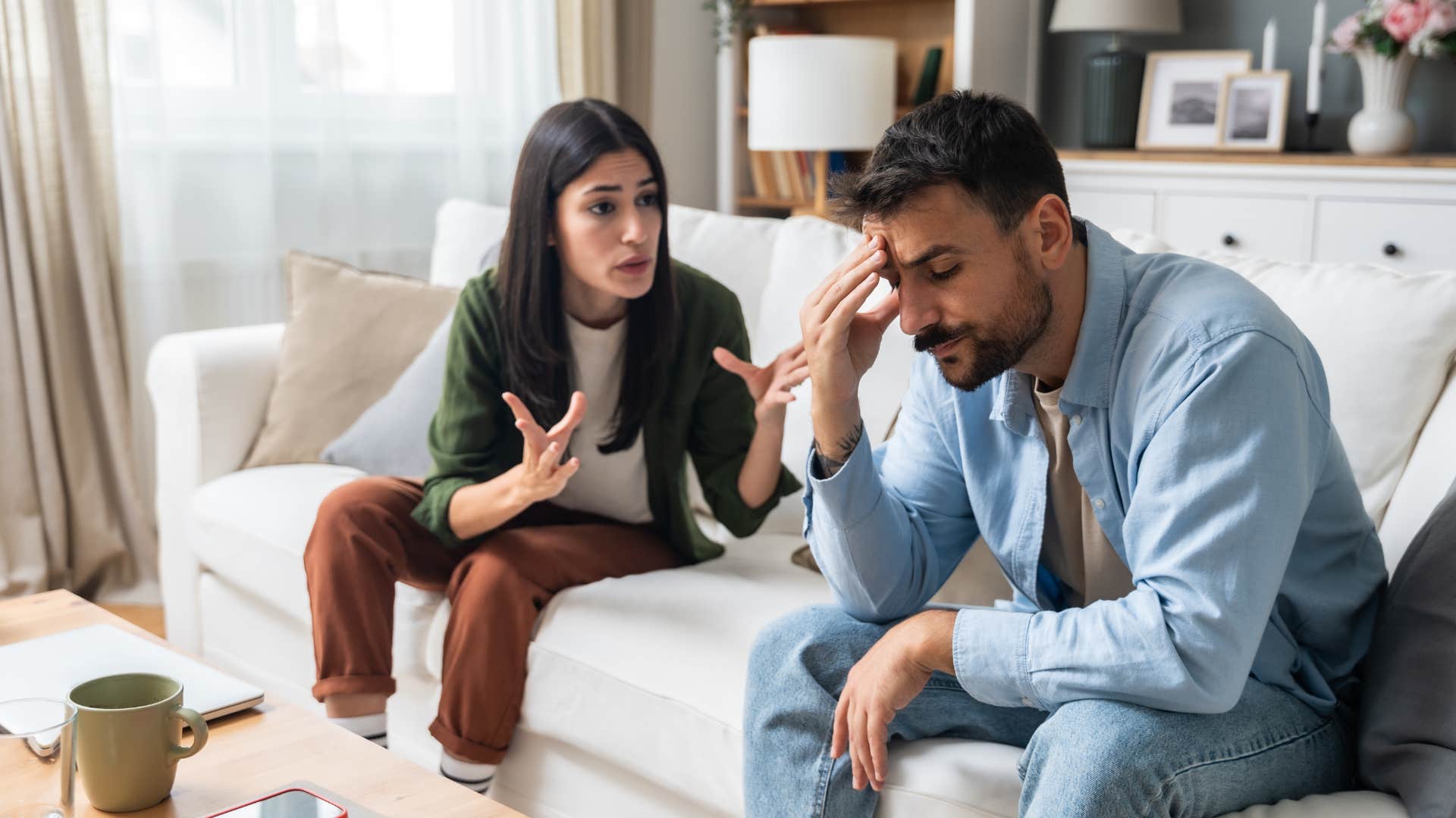 ungrateful man hanging his head in shame as woman yells at him