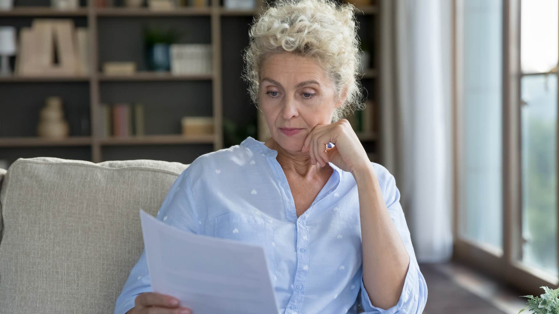 woman reading unopened mail and bills at home