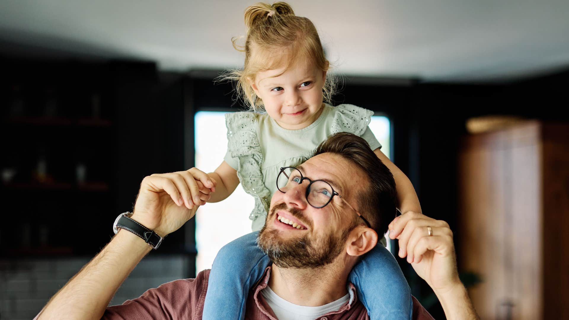 dad holding daughter on his shoulders making it fun