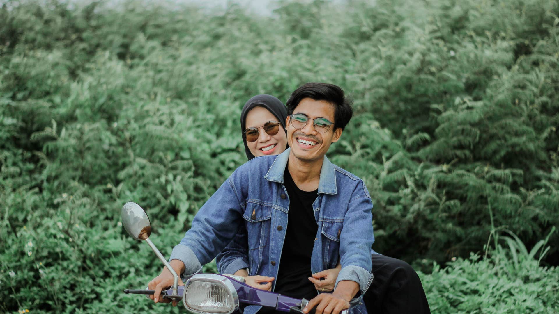 couple on a moped with wife whispering im proud of you to husband