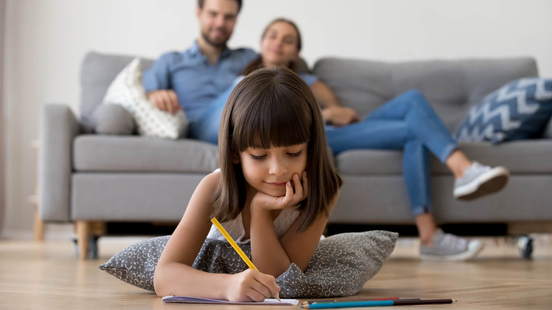 Focused daughter writes while both parents smile showing change forever