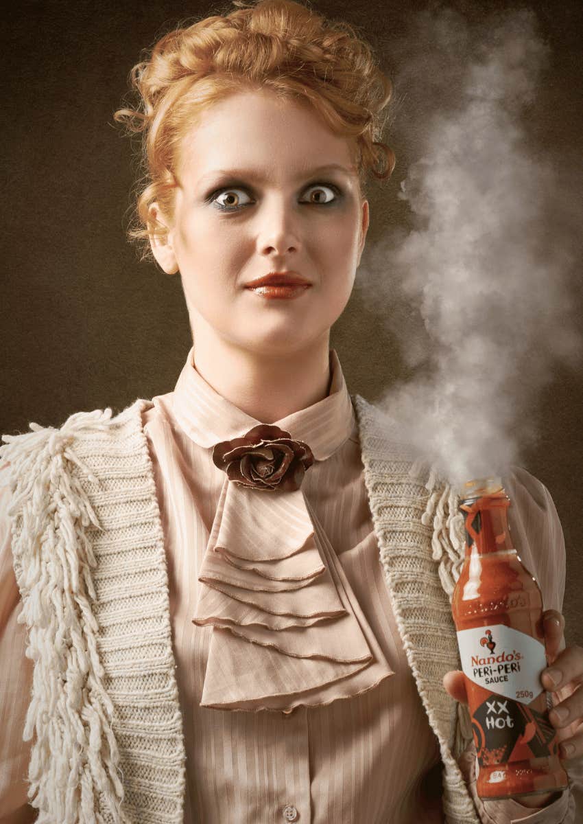 intense expression on woman holding streaming hot sauce bottle